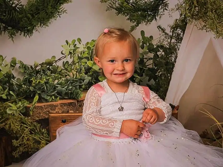 Peau, Sourire, Plante, Yeux, Dress, Flash Photography, Happy, Iris, Bambin, Bridal Clothing, Baby & Toddler Clothing, Herbe, Arbre, Formal Wear, Wedding Ceremony Supply, Event, Blond, Gown, Assis, Enfant, Personne, Joy