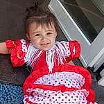 Facial Expression, Sourire, Sleeve, Baby & Toddler Clothing, Dress, Happy, Rose, Red, Waist, Bambin, Thigh, Trunk, Human Leg, Pattern, Fun, Ruffle, Event, Day Dress, Holiday, Fashion Accessory, Personne, Joy