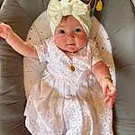 Visage, Joue, Peau, Yeux, Dress, Blanc, Human Body, Baby & Toddler Clothing, Sleeve, Textile, Baby, Iris, Rose, Yellow, Embellishment, Happy, Bambin, Day Dress, Comfort, Chair, Personne, Headwear